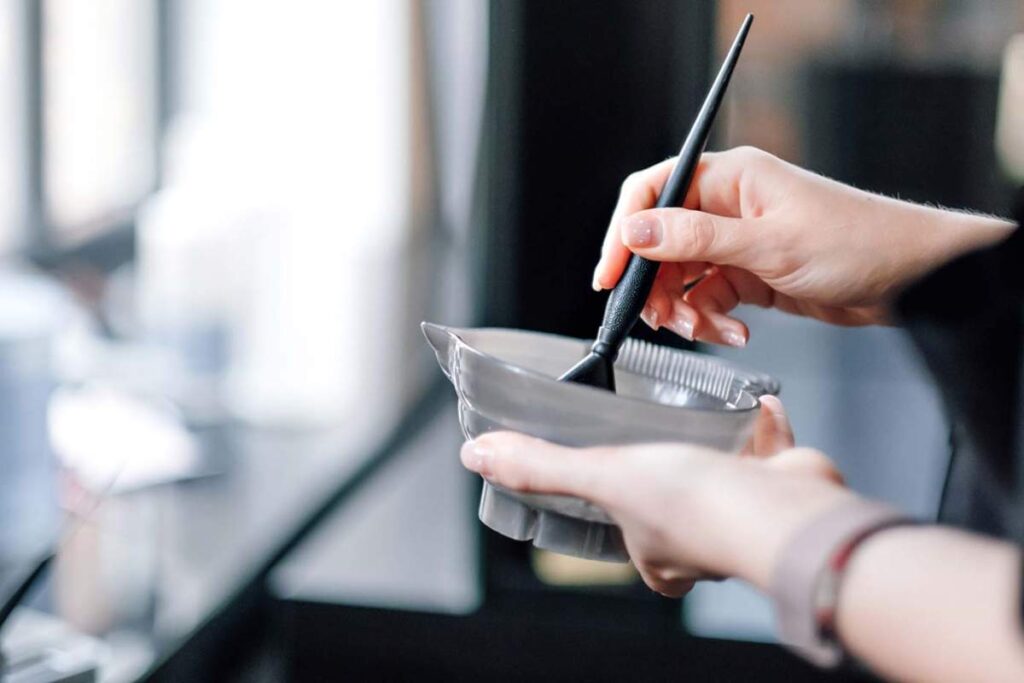 A hairstylist holding a mirror up to a client's face while discussing possible haircut styles.