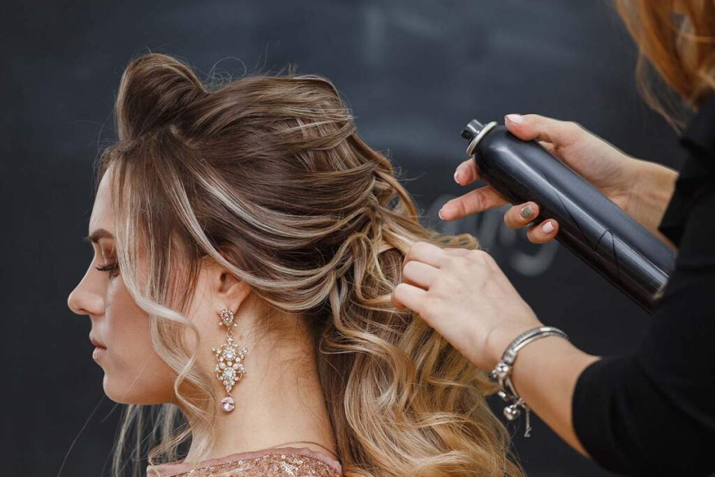 Person lifting fine hair at the roots with a round brush while blow-drying in a bright bathroom.